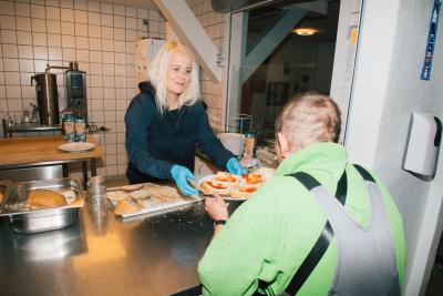En medarbejder serverer mad i Kirkens Korshærs varmestue i Aalborg