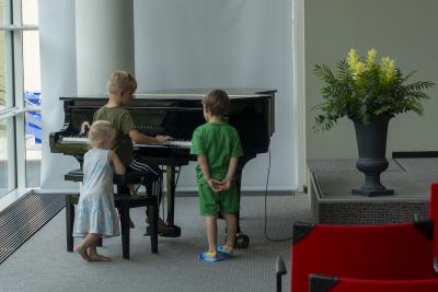Tre børn leger med et klaver på en ferielejr med Kirkens Korshær