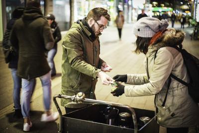 medarbejder giver suppe til kvinde på gaden