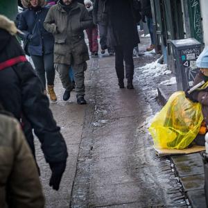En hjemløs kvinde sidder på strøget og sælger et hjemløsemagasin